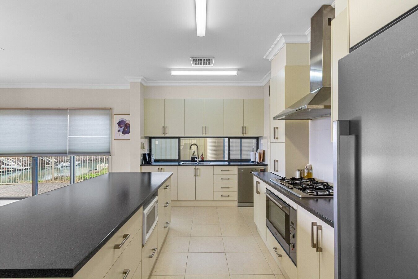 A modern kitchen with a large island, stainless steel appliances, and a view of a bridge.