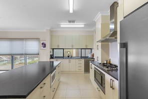 A modern kitchen with a large island, stainless steel appliances, and a view of a bridge. - Latitude 39 – Luxury Waterfront Living on Wallaroo Marina (Wallaroo)