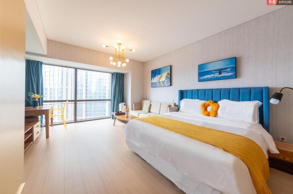 Habitación de hotel con una cama grande, un escritorio, una silla y vistas a la ciudad a través de la ventana.