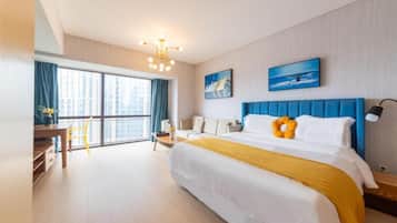 Habitación de hotel con una cama grande, un escritorio, una silla y vistas a la ciudad a través de la ventana.