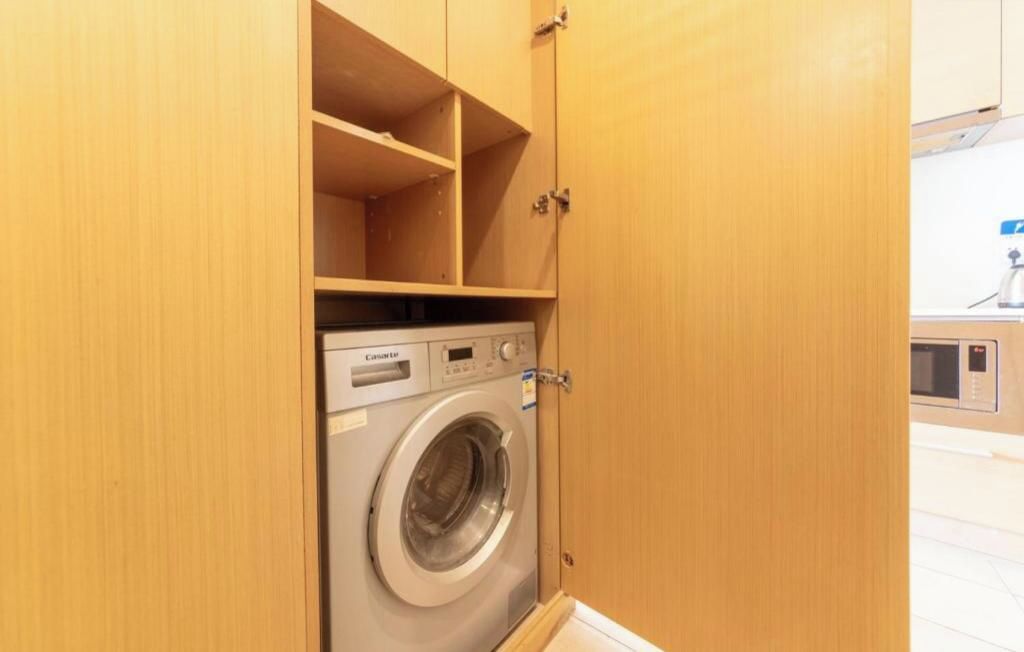 A compact, wooden laundry room with a front-loading washing machine.