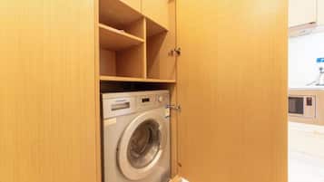 A compact, wooden laundry room with a front-loading washing machine.
