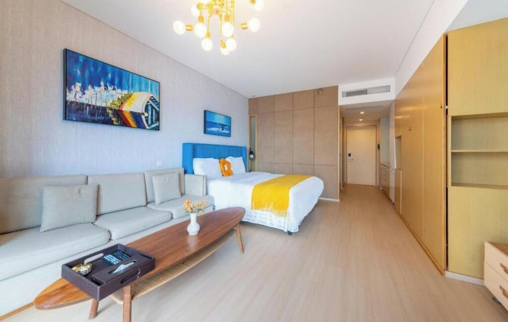 A hotel room with a bed, sofa, and a dining table.