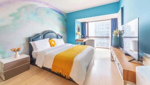 Ein Hotelzimmer mit Bett, Schreibtisch, Fernseher und großem Fenster.