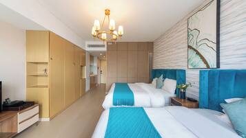 Habitación de hotel con dos camas, un armario de madera, una kitchenette y un cuadro abstracto grande en la pared.