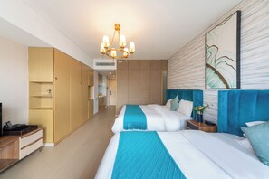 Habitación de hotel con dos camas, un armario de madera, una kitchenette y un cuadro abstracto grande en la pared.