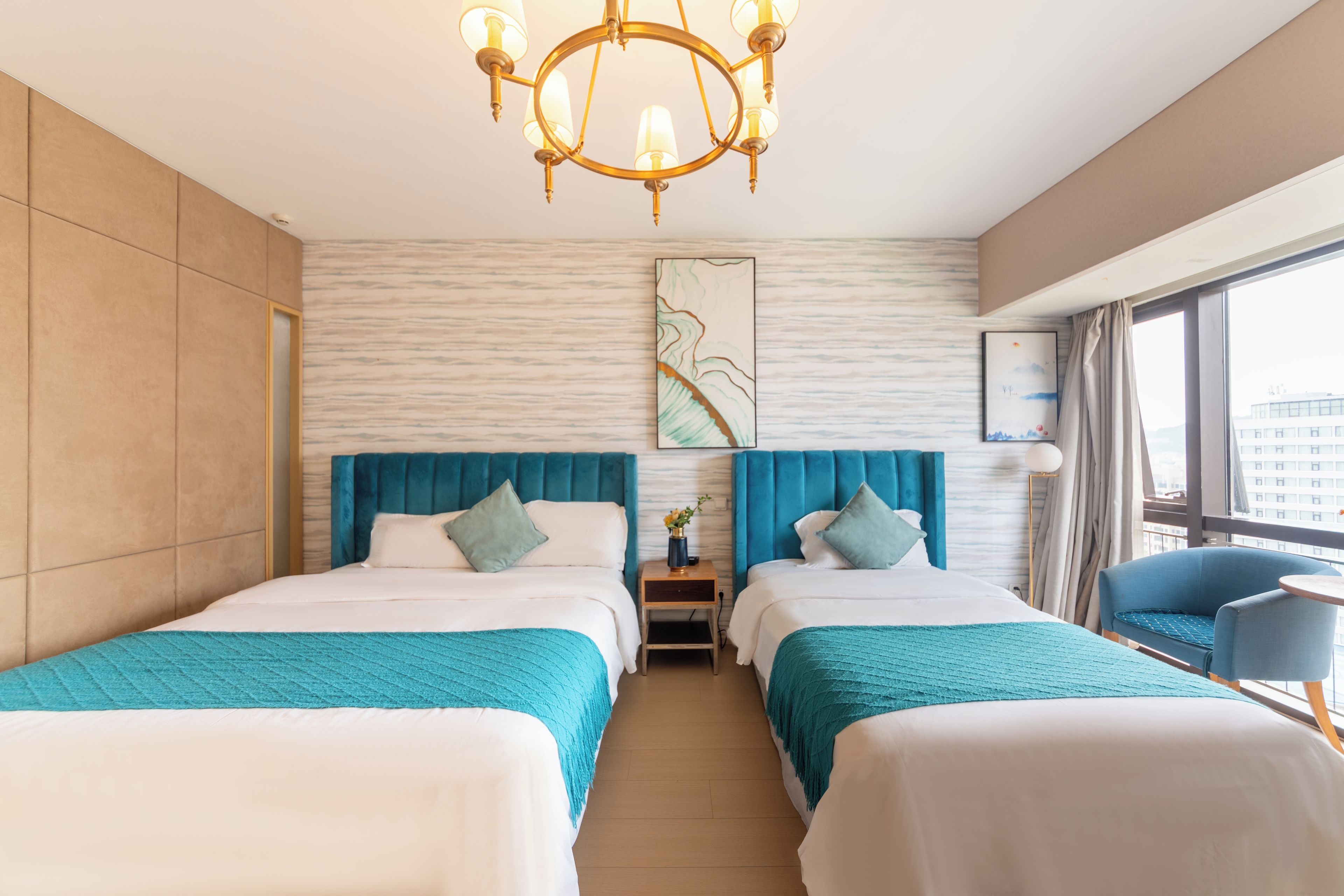 Habitación de hotel con dos camas, un candelabro, un cuadro y vistas de la ciudad.
