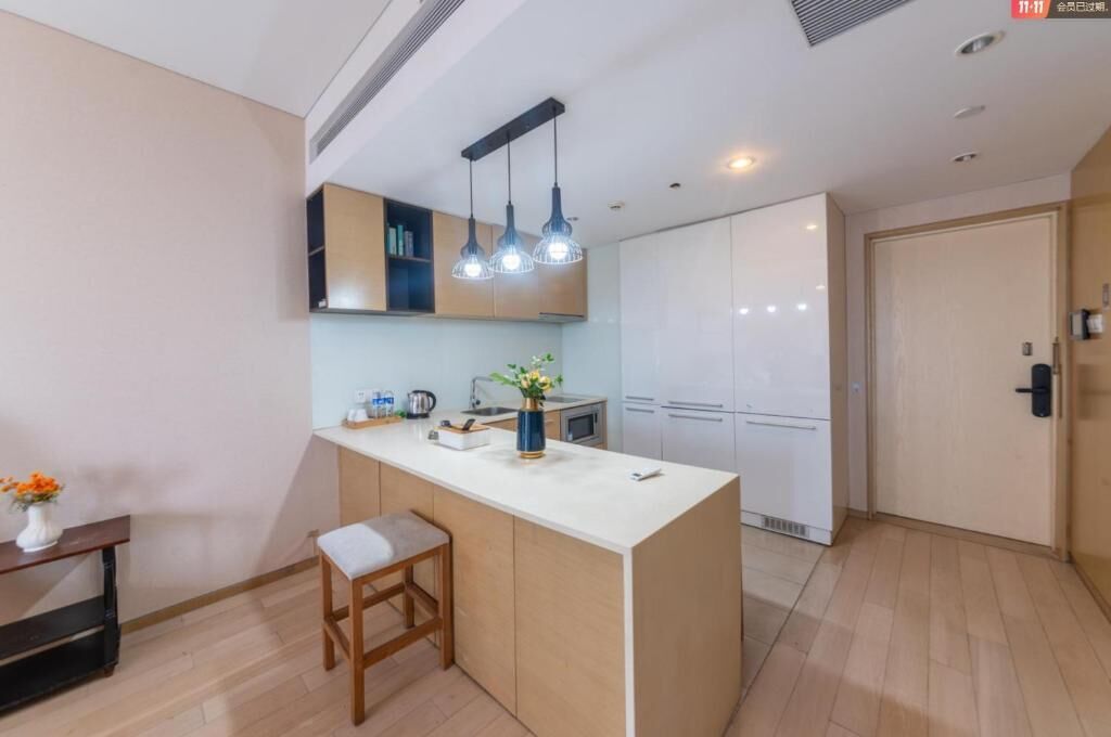 A modern kitchen with a central island, pendant lighting, and a view to the living area.