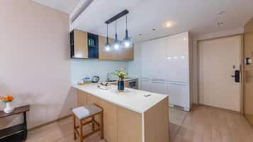 A modern kitchen with a central island, pendant lighting, and a view to the living area.