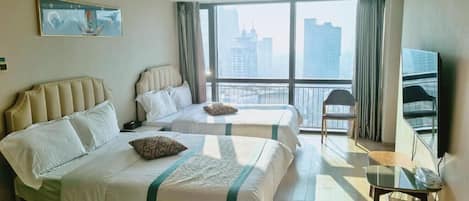 Habitación de hotel con dos camas, televisión, balcón y vista a la ciudad.