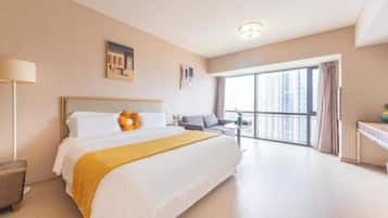 Habitación de hotel con una cama grande, un escritorio, una silla y vista a la ciudad por la ventana.