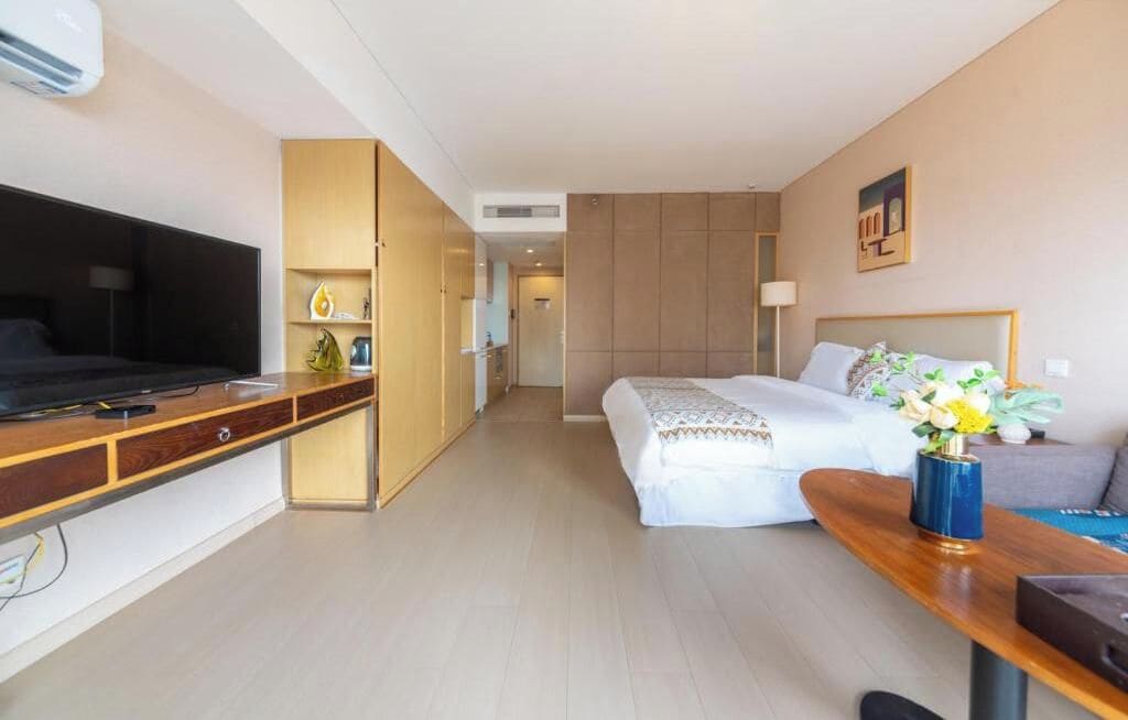 A hotel room with a bed, a desk, a television, and a wardrobe.