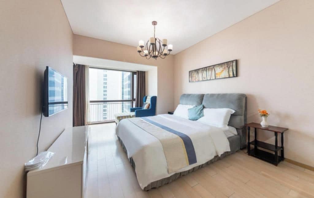 Una habitación de hotel con cama, televisión, escritorio, silla, ventana y candelabro.