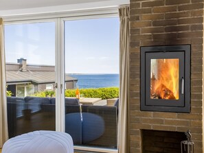 A room with a fireplace, a large sliding glass door with a view of the sea, and a cozy seating area. - "Andriette" - 50m from the sea by Interhome (Haderslev)