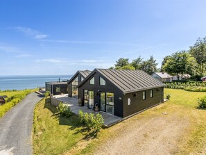 A modern house with a large glass door, a paved driveway, and a view of the sea. - "Andriette" - 50m from the sea by Interhome (Haderslev)