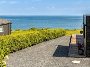 A coastal property with a gravel driveway leading to a wooden deck, a small building, and a view of the sea. - "Andriette" - 50m from the sea by Interhome (Haderslev)