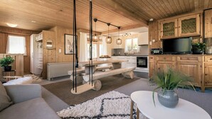A cozy cabin interior with a wooden ceiling, a dining area, a kitchen, and a living room with a sofa and a coffee table. - Chalet Agathli, (Flumserberg Bergheim), by Interhome (Flumserberg Bergheim)
