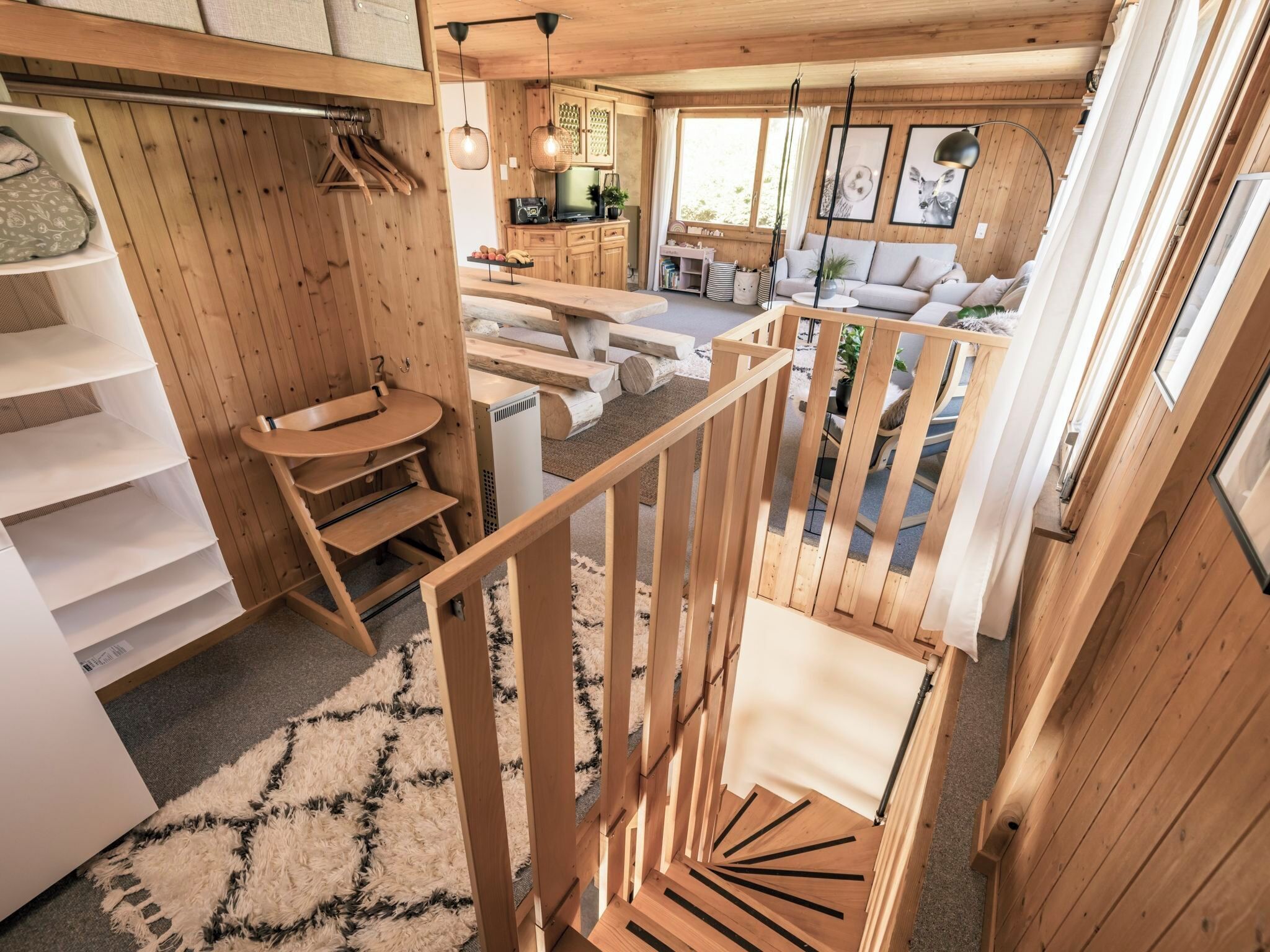 Un intérieur en bois avec un escalier, un canapé et un coin cuisine.