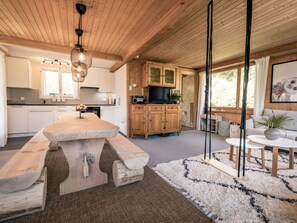 A modern kitchen with wooden cabinets, a dining table, and a large window. - Chalet Agathli, (Flumserberg Bergheim), by Interhome (Flumserberg Bergheim)