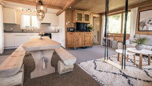 A spacious kitchen with a central island, wooden cabinets, and a dining area with a round table. - Chalet Agathli, (Flumserberg Bergheim), by Interhome (Flumserberg Bergheim)