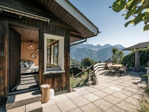 A wooden cabin with a patio, a dining area, and a view of mountains. - Chalet Agathli, (Flumserberg Bergheim), by Interhome (Flumserberg Bergheim)