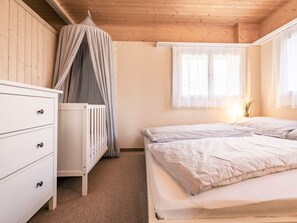 A bedroom with a bed, a dresser, a window with curtains, and a wooden ceiling. - Chalet Agathli, (Flumserberg Bergheim), by Interhome (Flumserberg Bergheim)