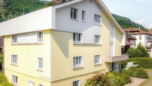 Ein mehrstöckiges Wohngebäude mit flachem Dach, zahlreichen Fenstern und einem Balkon.
