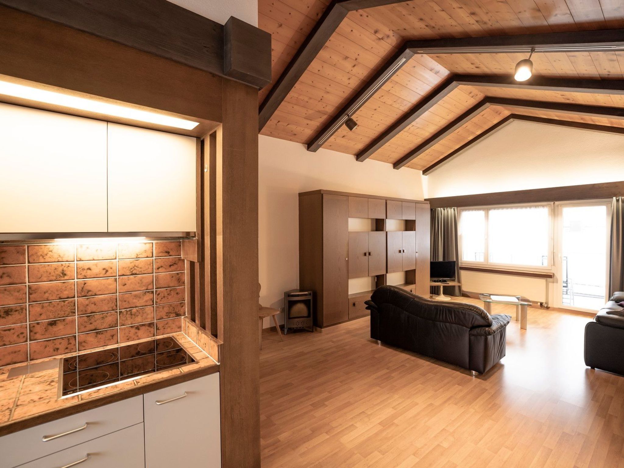 A spacious living area with a fireplace, wooden flooring, and a large window.