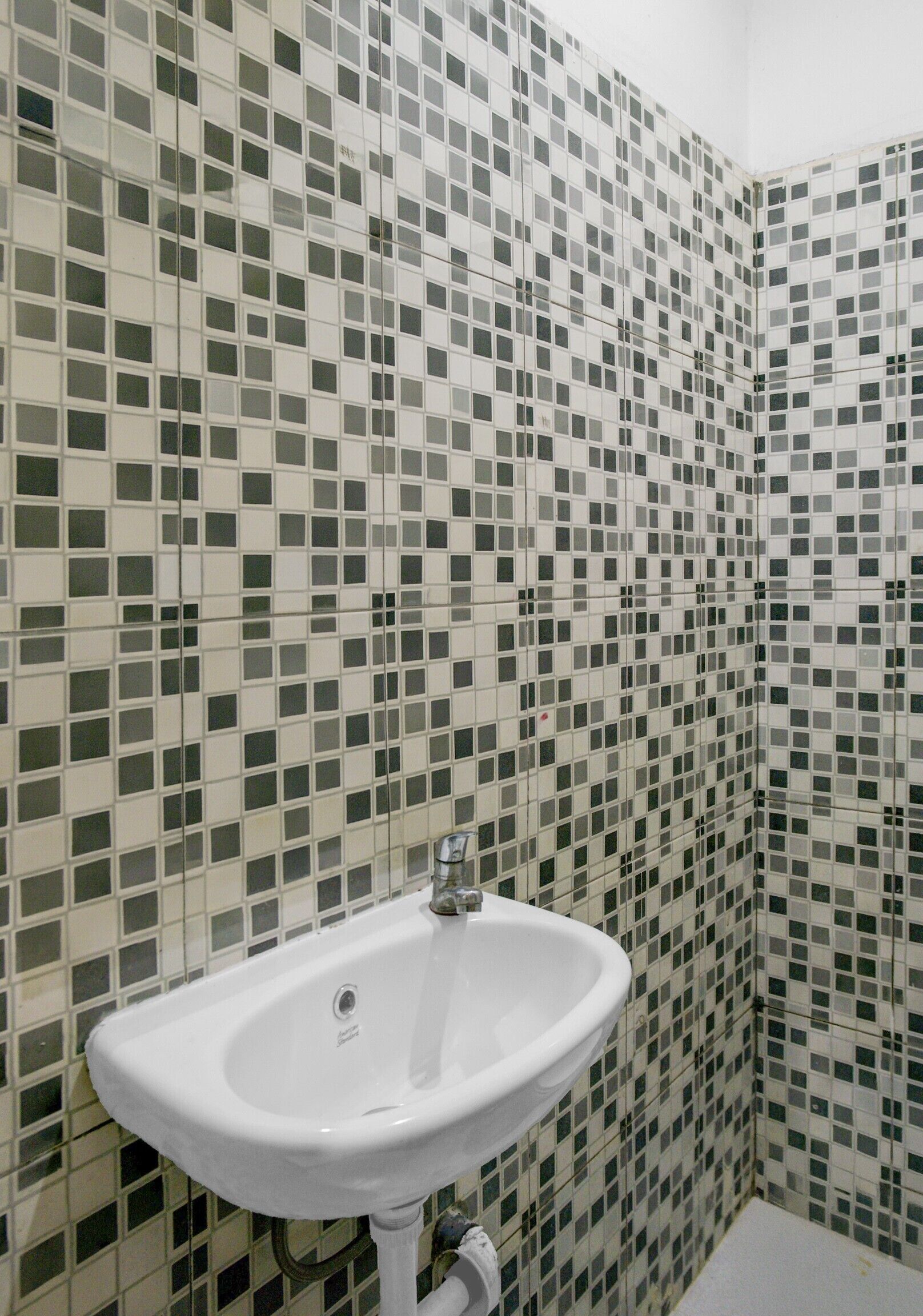 Un bagno con un lavandino bianco e pareti rivestite di mosaici.