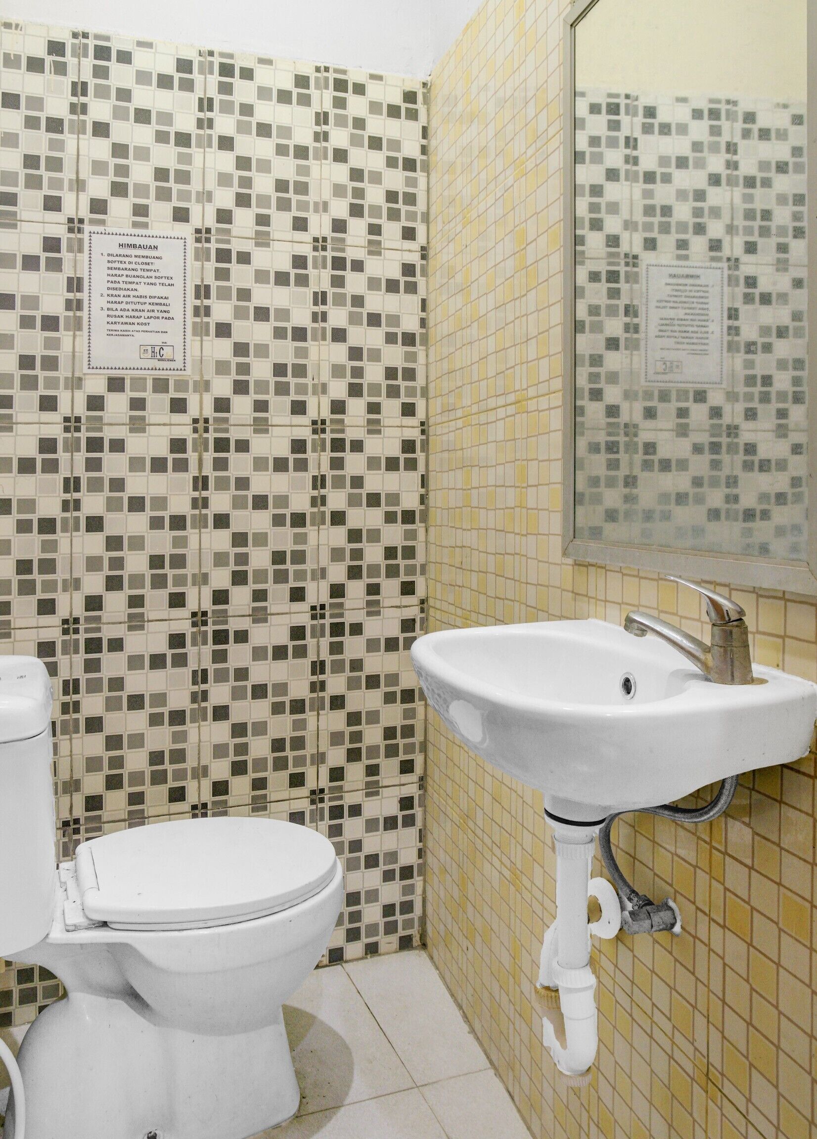 A bathroom with a toilet, sink, and tiled walls.