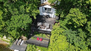 Luchtbeeld van een huis, omringd door weelderige groene begroeiing, met een terras en een zitgedeelte buiten.