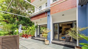 Un edificio moderno con entrada de vidrio, mesas al aire libre y plantas en macetas.