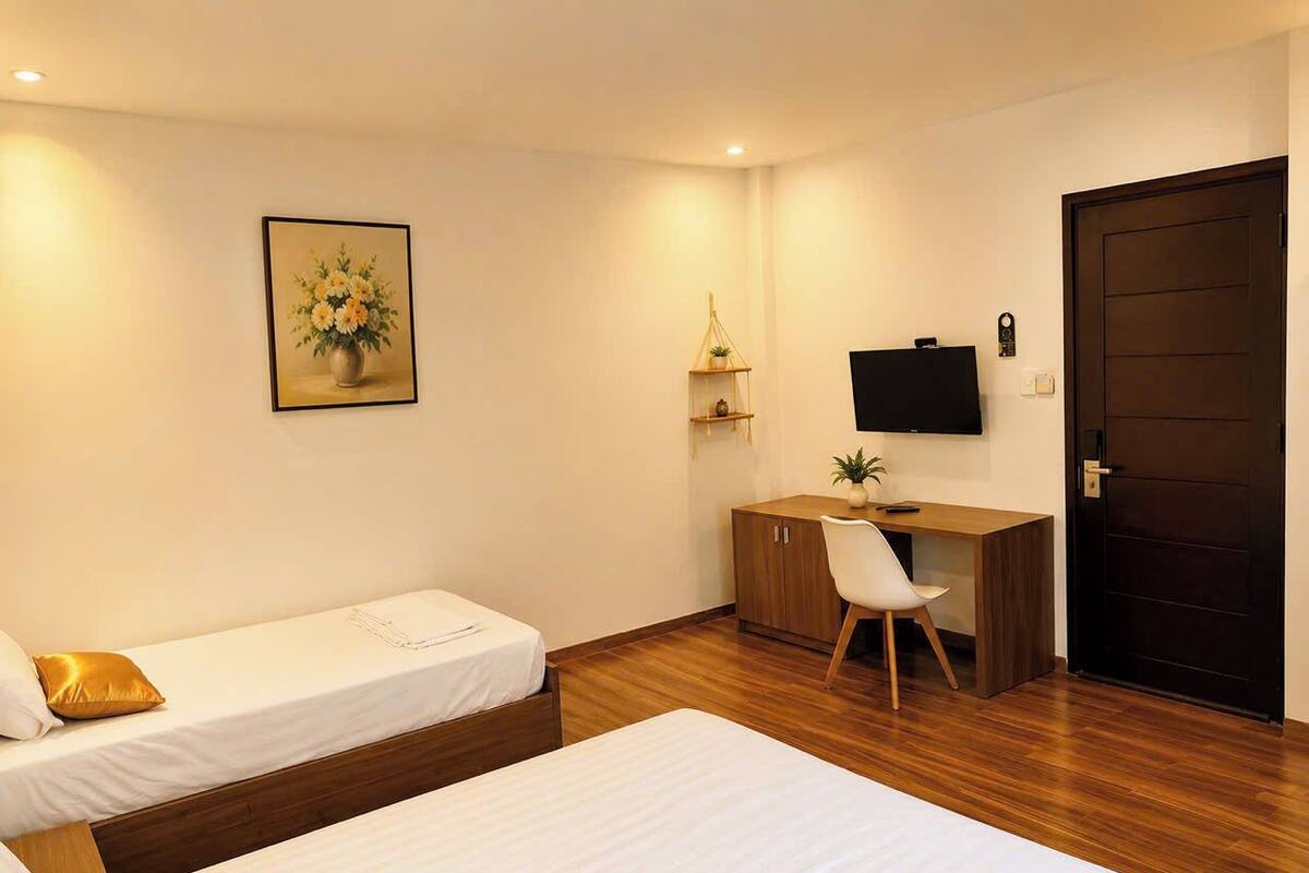 Ett hotellrum med två sängar, ett skrivbord, en stol, en tv och en dörr.