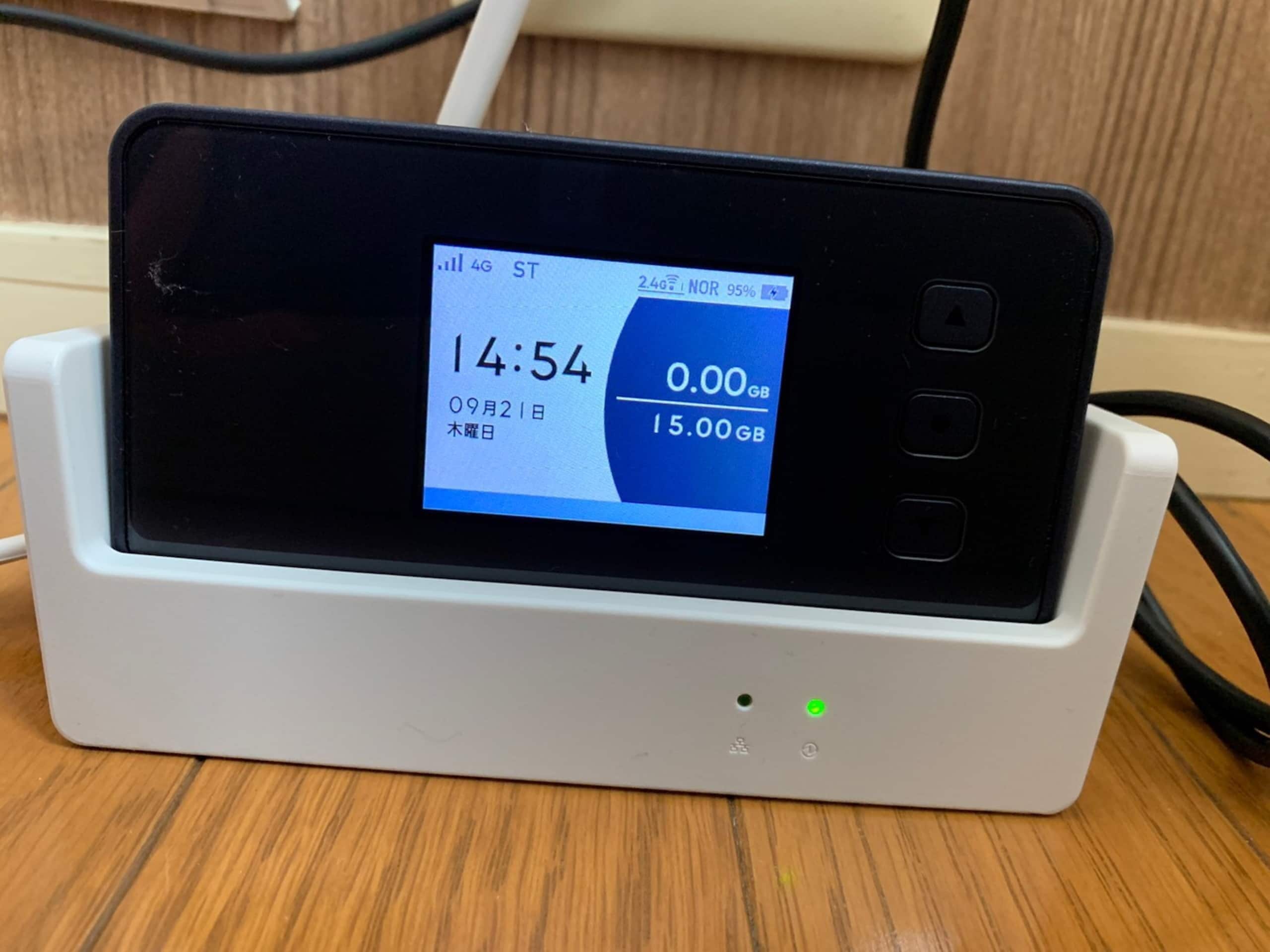 Un smartphone en cours de chargement sur un support blanc, avec un écran affichant l’heure, le niveau de batterie et la qualité du signal réseau.