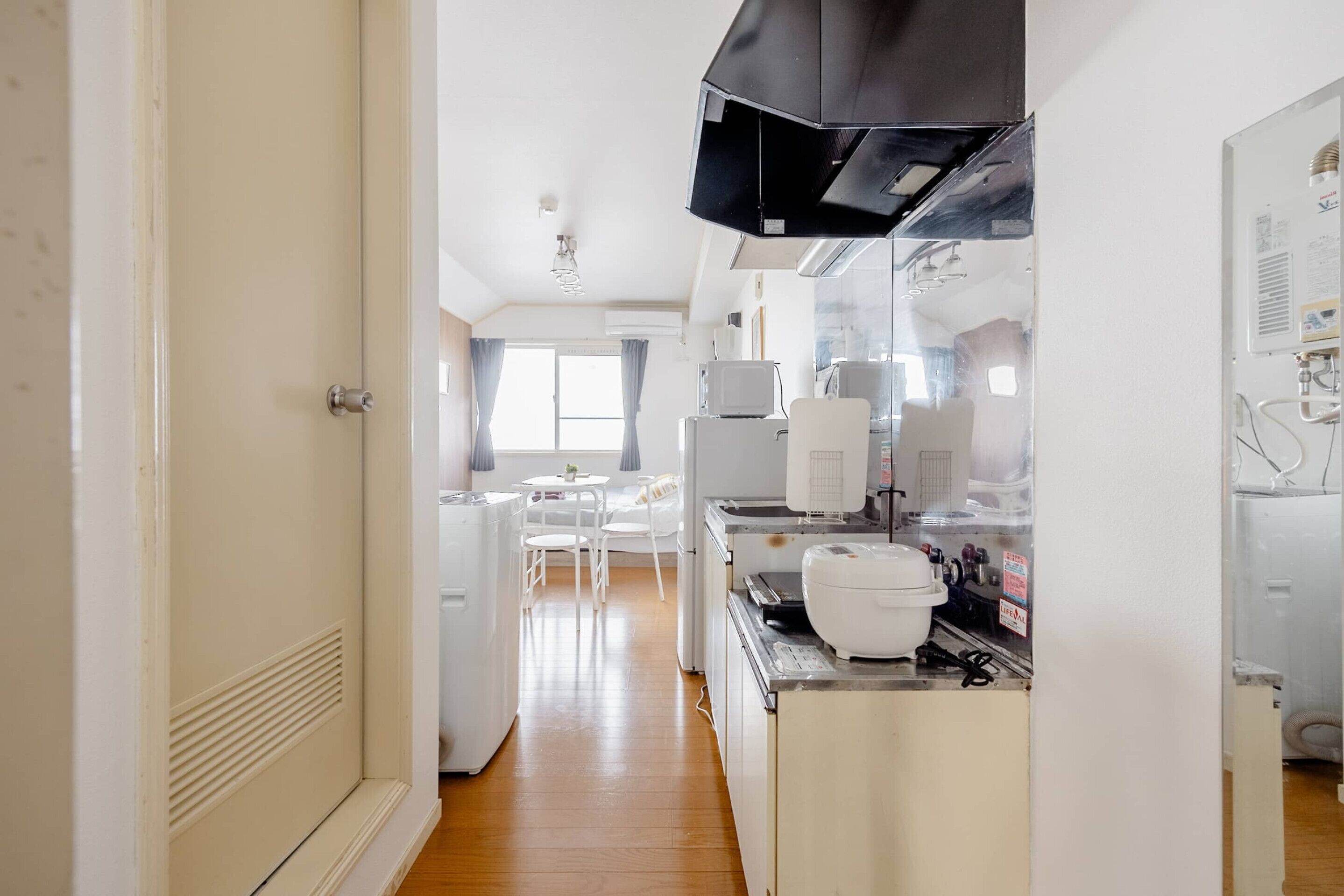 A kitchen with a black range hood, white appliances, and a dining area with a table and chairs.