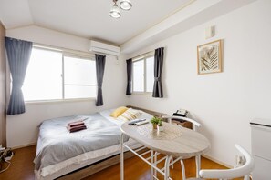 Une chambre à coucher avec un lit, une table de chevet et une fenêtre avec des rideaux.