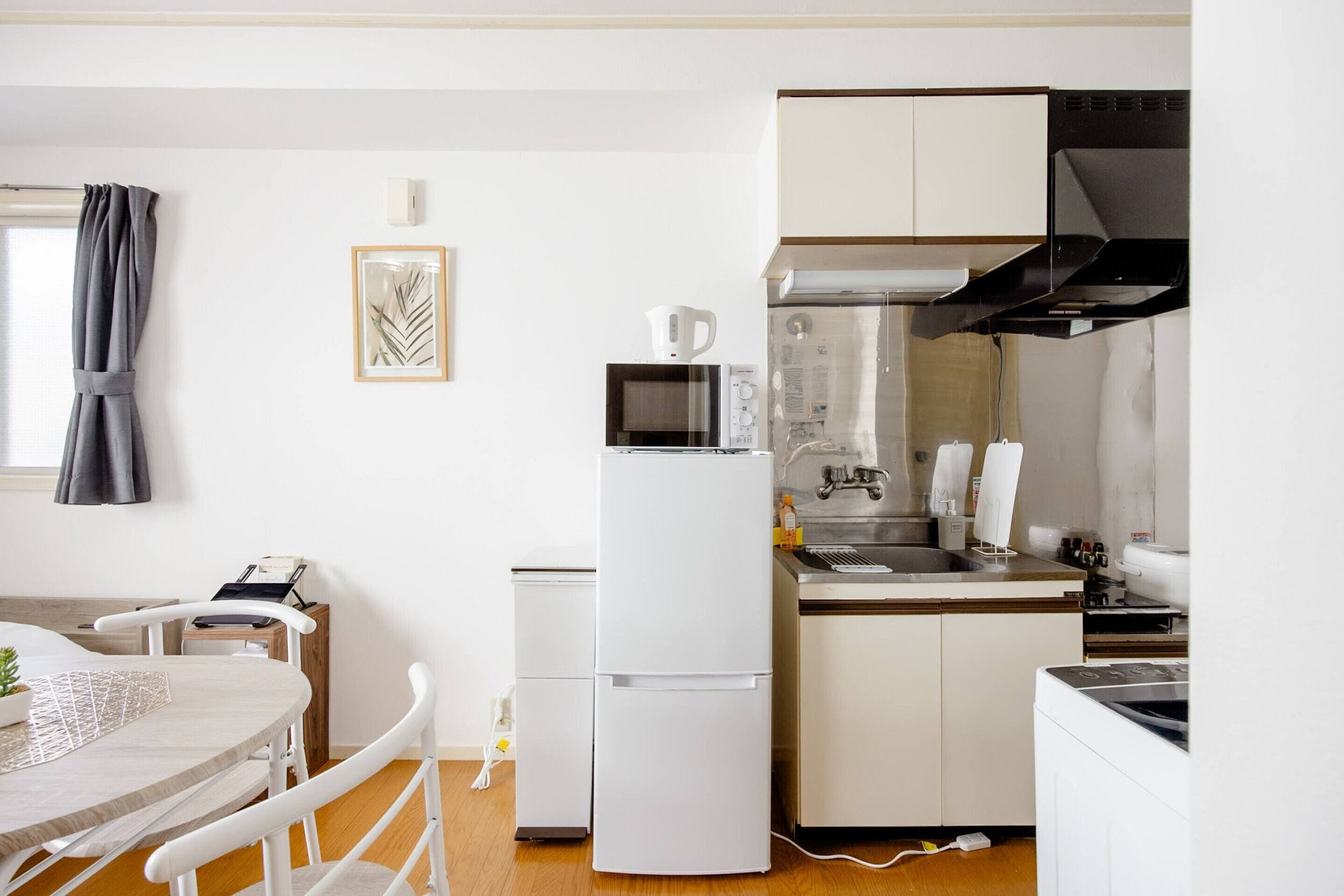 A compact kitchen with a refrigerator, microwave, sink, and a small dining area with a table and chairs.