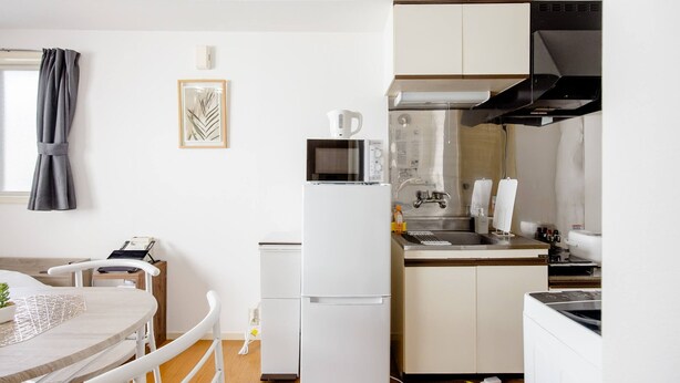 Une cuisine compacte équipée d’un réfrigérateur, d’un four à micro-ondes, d’un évier et d’un petit coin repas avec une table et des chaises.
