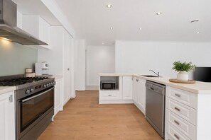 Una cocina moderna con armarios blancos, electrodomésticos de acero inoxidable y piso de madera.