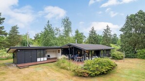 Et moderne hus med en overdækket terrasse og garage.