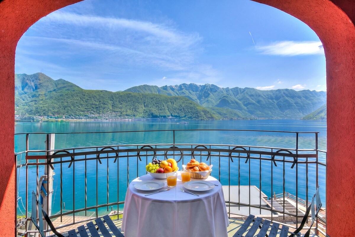 A table with breakfast items and a view of a lake and mountains.