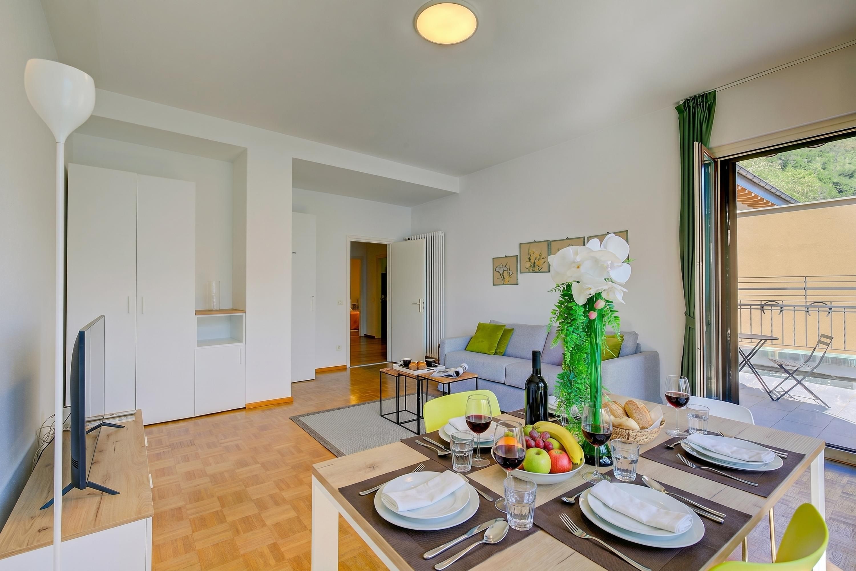 Un comedor con una mesa preparada para cuatro, un televisor y vistas al exterior.