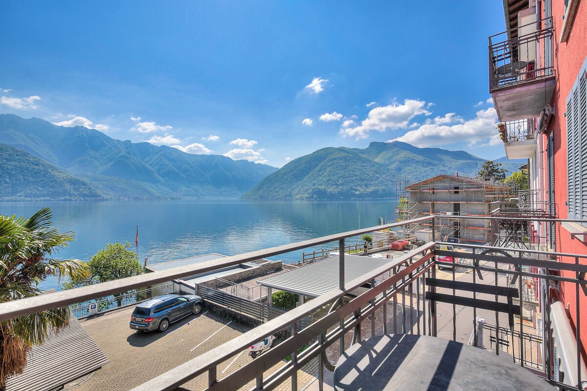 A building with a balcony overlooking a lake and mountains.