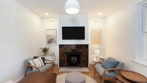 A living room with a fireplace, a flat-screen TV, and two sofas.