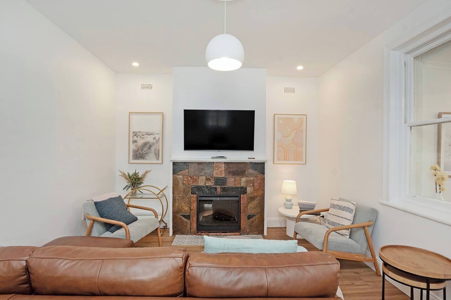 A modern living room with a fireplace, leather sofa, and two armchairs.