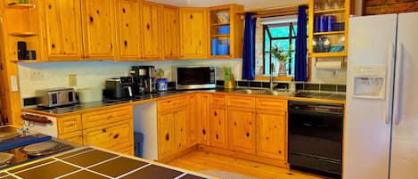 Een keuken met houten kastjes, een magnetron, een koelkast en een koffiezetapparaat.