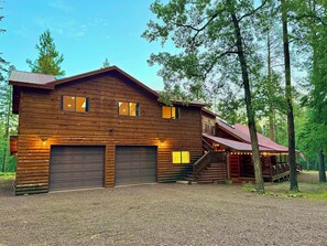 A two-story log cabin with a covered porch and a staircase leading to the upper level.