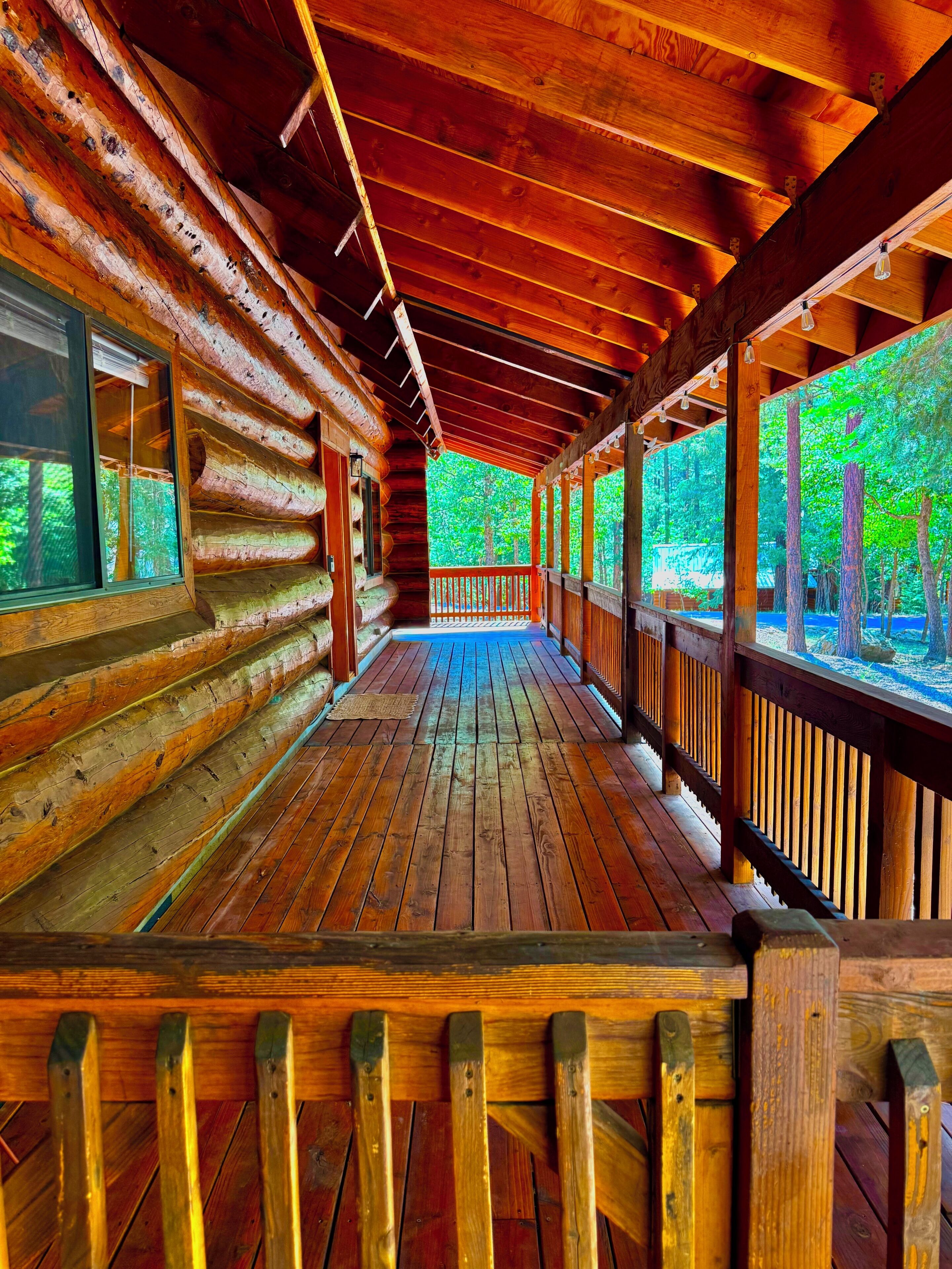Une cabane en bois avec un porche couvert et de grandes fenêtres.