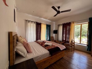 Ein Schlafzimmer mit einem Holzbett, einem Deckenventilator, einem Fernseher und einem Fenster mit Vorhängen.