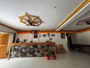 Ein Empfangsbereich mit einer Steinwand, einem Holzbüro und einem Deckenventilator.